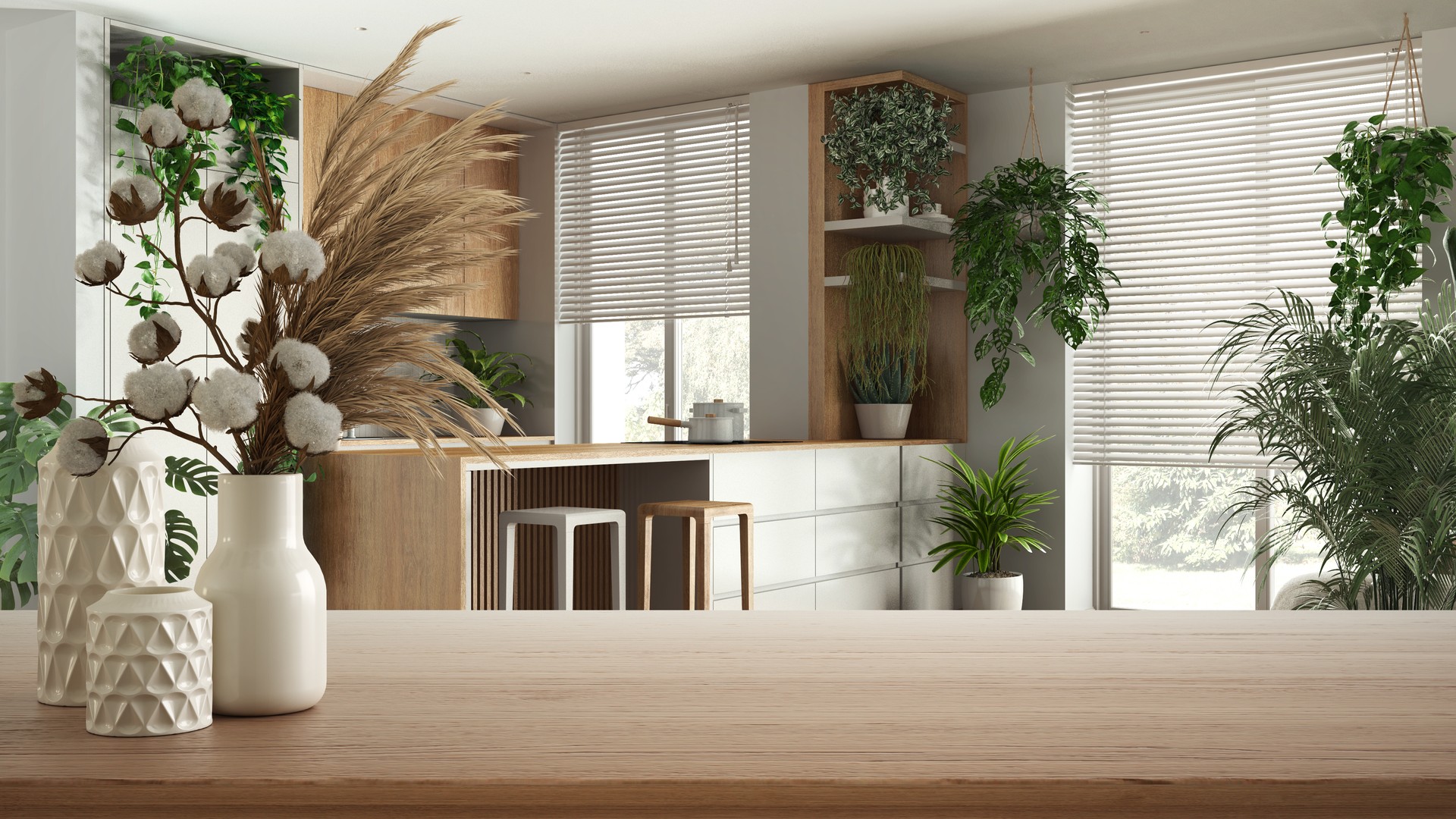 Wooden table, desk or shelf close up with ceramic vases with cotton flowers over modern kitchen with island and many houseplants, urban jungle interior design concept