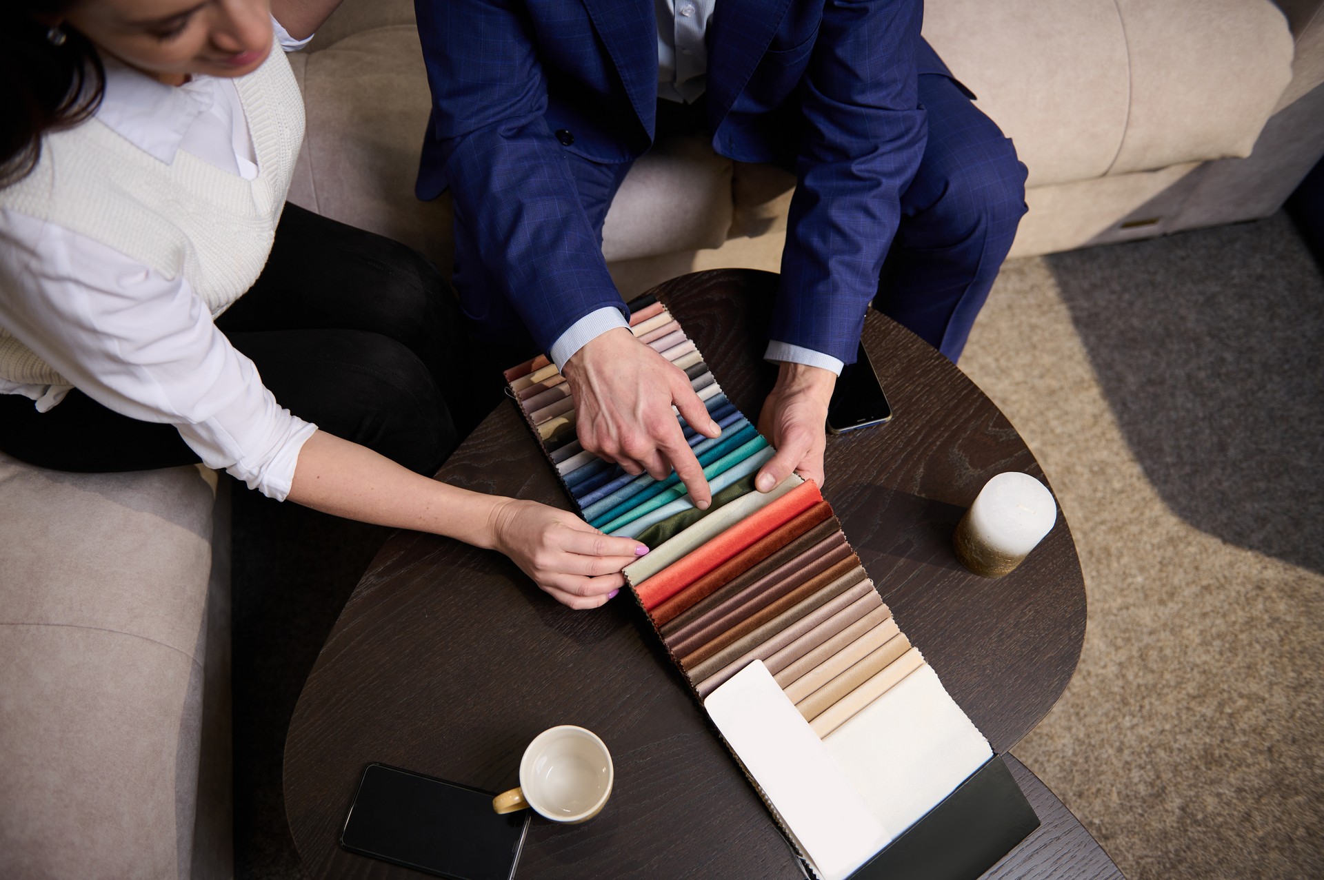 Focus on samples of colored fabrics for upholstered furniture. Top view of couple choosing color and fabric texture for upholstery sofa in the home. Interior design concept